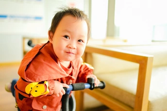 一个微笑的小孩子骑着小滑板车 后面跟着一个男孩