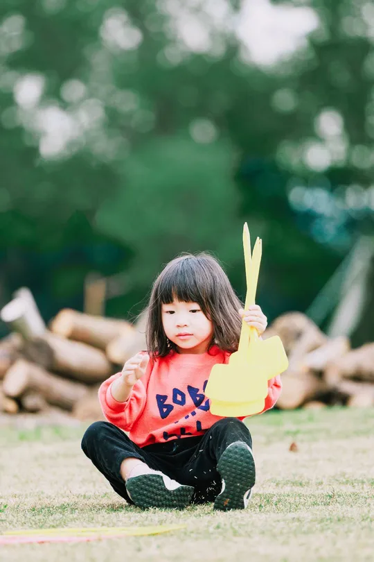 一个小女孩在公园里拿着一个有纸的棍子玩