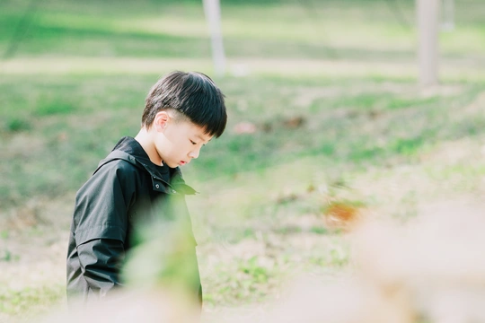 一个小男孩站在草地上看着另一个小孩子