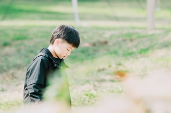一个小男孩站在草地上看着另一个小孩子