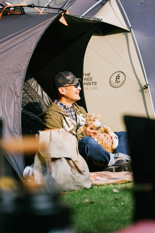 一个坐在帐篷里抱着一只猫和一只狗的男人