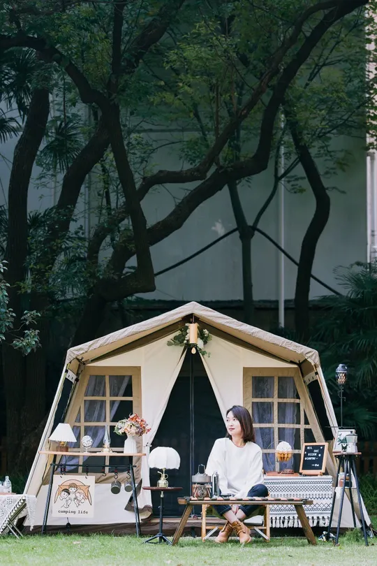 一个妇女坐在一个小帐篷外面 带着她的狗。