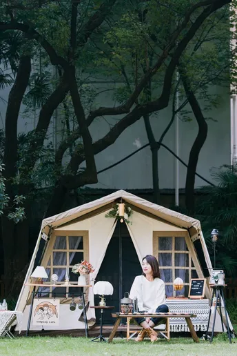 一个妇女坐在一个小帐篷外面 带着她的狗。