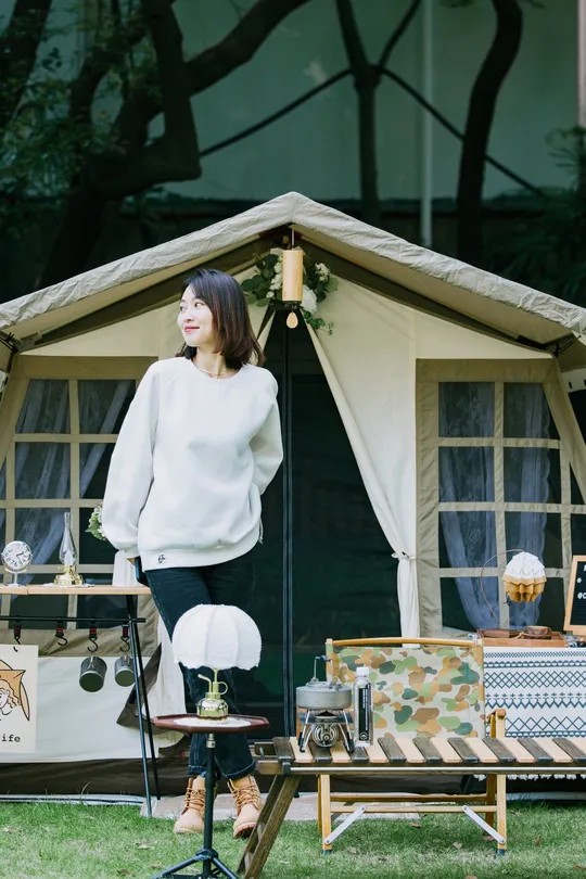 一位站在像房子一样的帐篷前面的女人