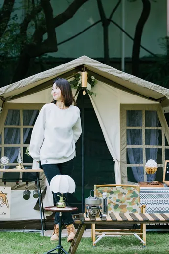 一位站在像房子一样的帐篷前面的女人