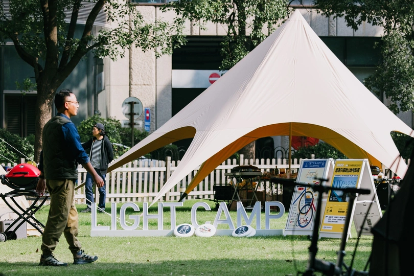 一个拿着飞盘的男人站在公园里的大型白色帐篷下 人们路过。