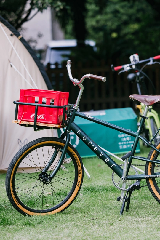 背景有帐篷的田地中停着一辆带红色篮子的自行车
