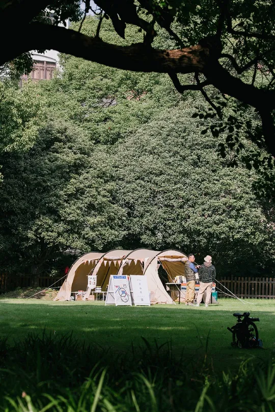 一些人在公园里带着一只狗在大型帐篷附近散步。