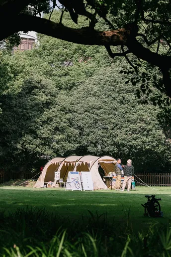 一些人在公园里带着一只狗在大型帐篷附近散步。