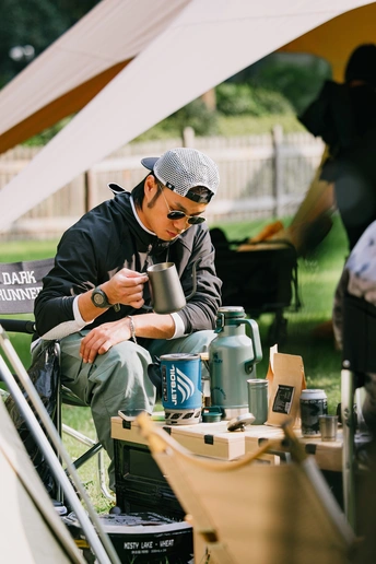 一个坐在帐篷下椅子上的男人拿着一个杯子