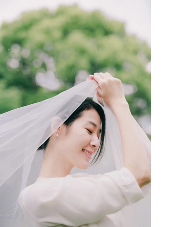 一位穿着白色婚纱的女子举着头纱在风中