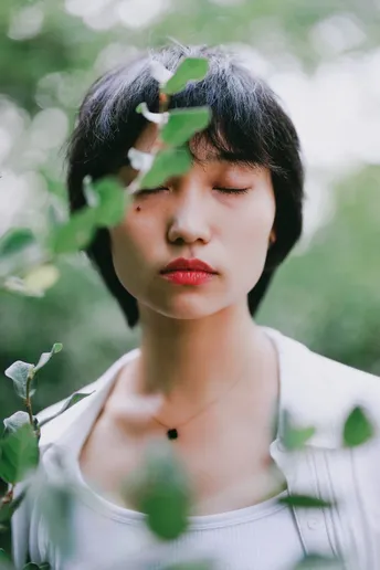 一位年轻女子在森林中的肖像 周围有白色的花朵和植物围绕在她脸上