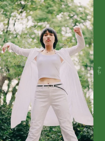 一位穿白色裤子的女人站在一棵棵树的森林中