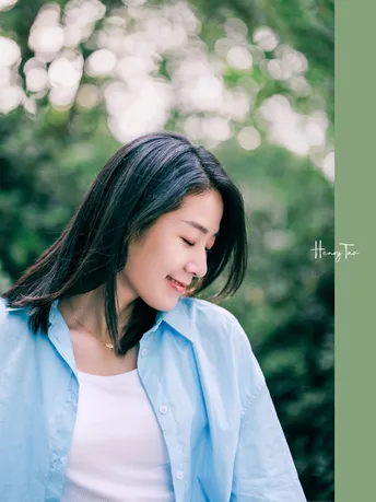 一张年轻女性穿着白色衬衫站在外面的照片