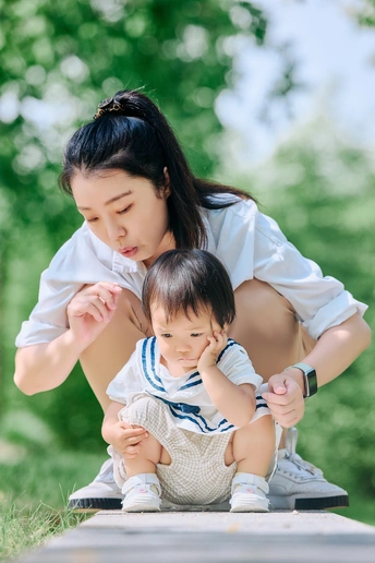 一位年轻女子抱着一个小宝宝在公园里玩耍