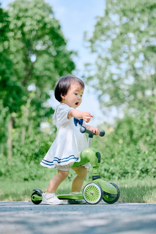 一个小女孩穿着裙子在公园里和小绿色玩具一起玩耍