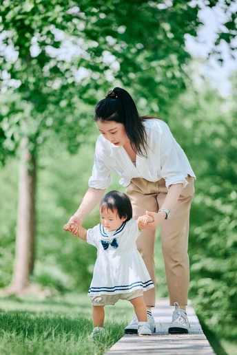 一位年轻女子牵着小女孩走过一座木桥