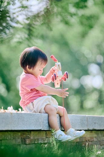 一个年轻女孩坐在公园墙上玩一个小玩具