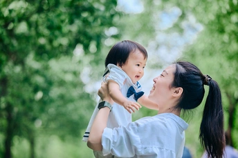 年轻母亲抱着她的小女儿在公园里玩耍