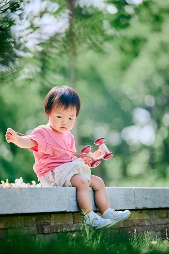 一个小女孩坐在公园里的小墙上 光着脚
