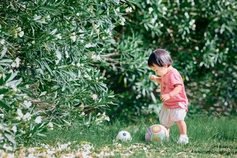 一个年轻女孩在一个小院子里踢足球 球站在草地上。
