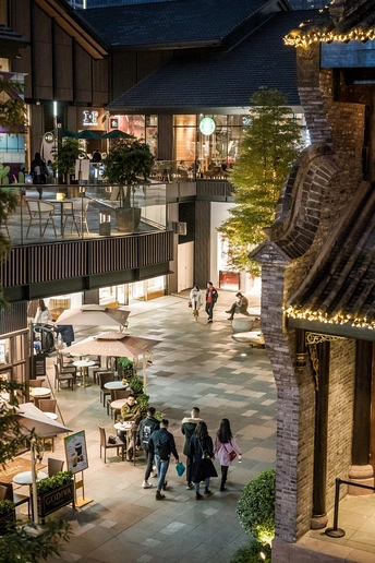 人们在夜晚的商场里走动 建筑物和餐厅上有灯光。