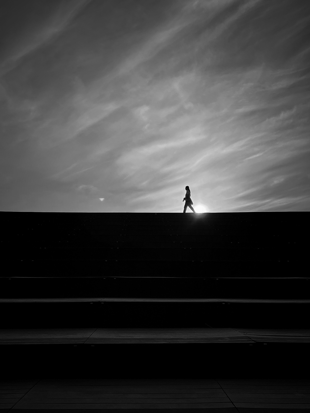 夕阳下 一个黑白色剪影 一个男子和一个女子正在散步 太阳在天空中低垂。