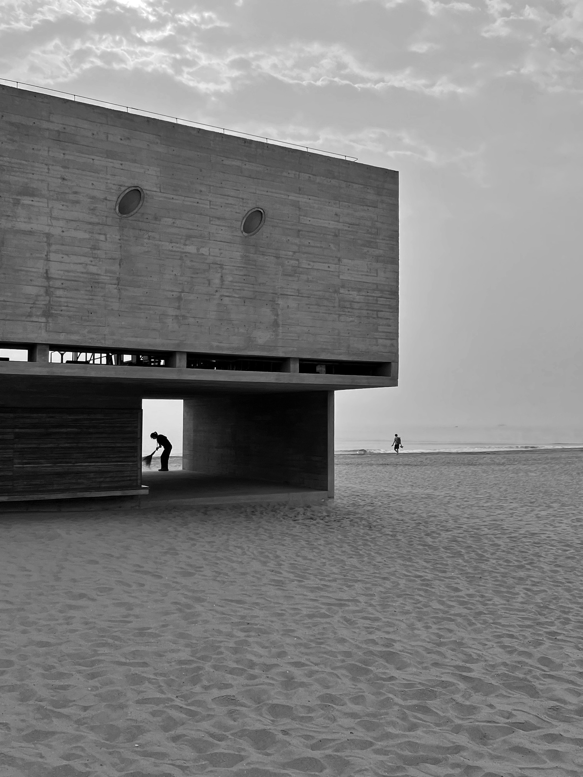 黑白照片 一个人在建筑附近的沙滩上滑板