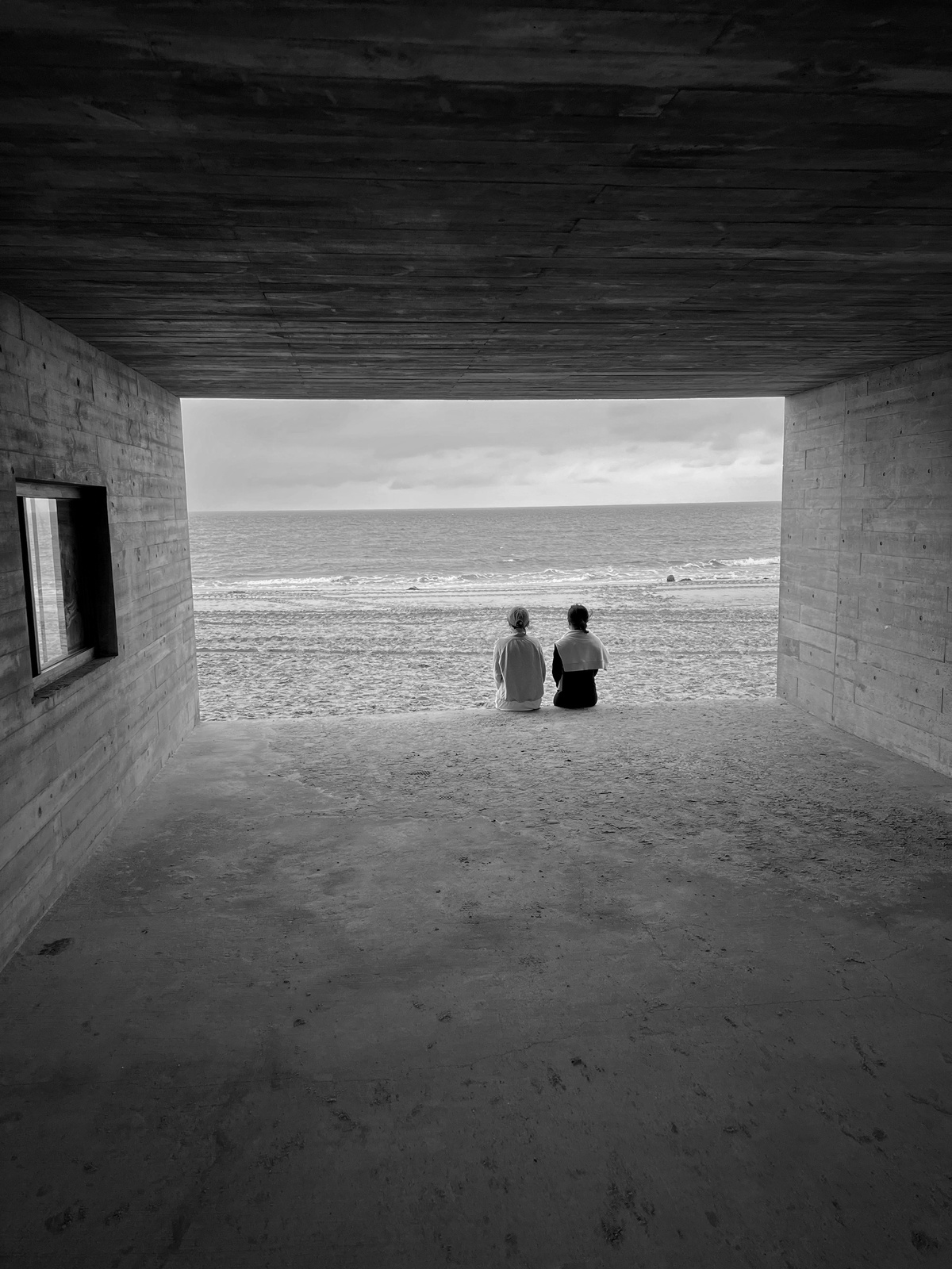 几对夫妇坐在隧道里 面向海滩和海洋 黑白照片