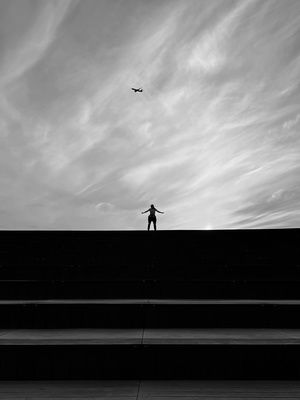 一片黑白的天空 一个人抬头看着天空中飞翔的风筝。