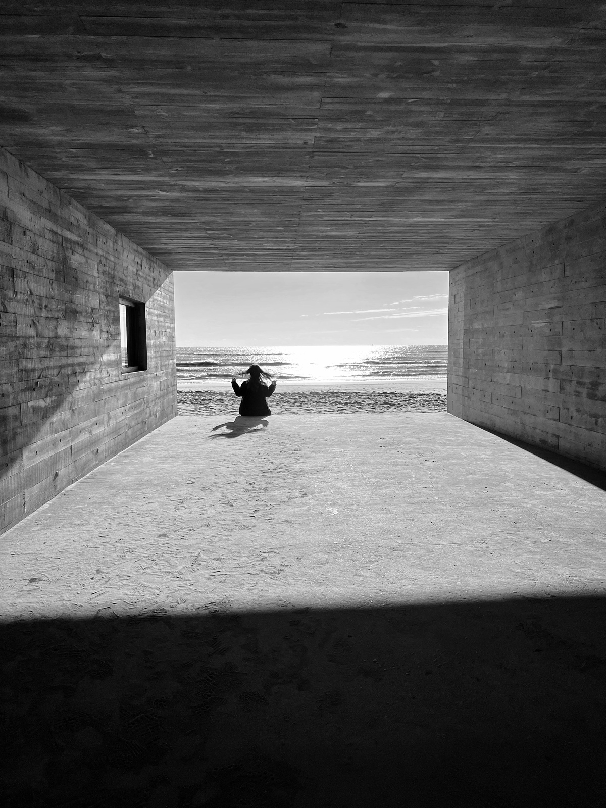 一个人坐在海滩下的隧道中央 黑白照片