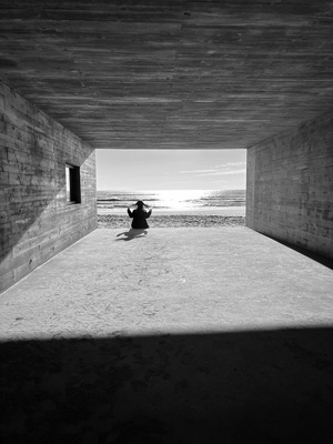 一个人坐在海滩下的隧道中央 黑白照片