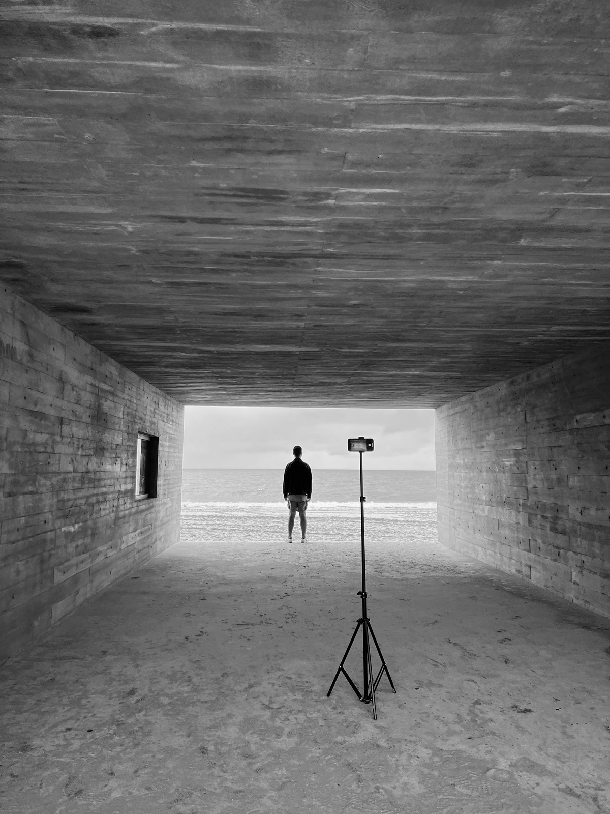 一个人站在一个隧道里 手里拿着一个三脚架相机。