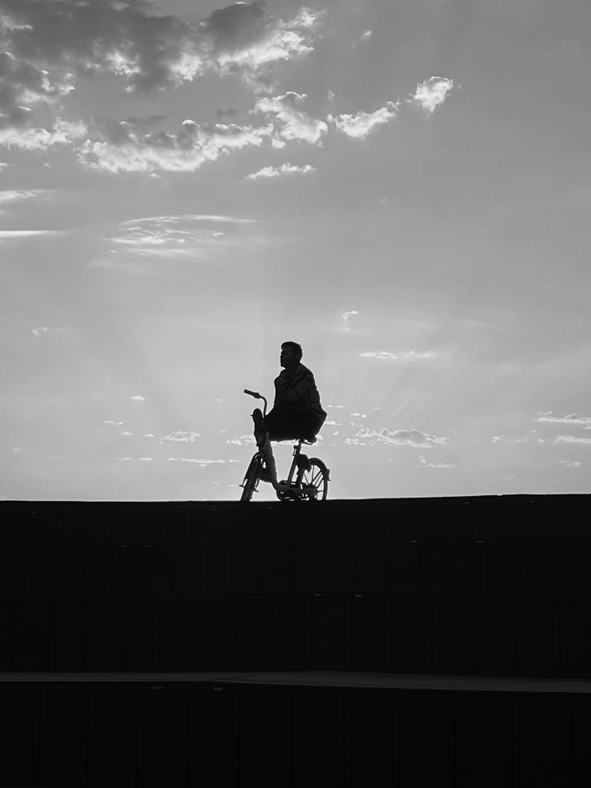 一个黑白剪影 一个人站在桥上 一个孩子骑自行车。