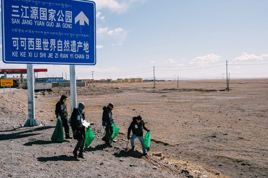 人们沿着一条路走 手里拿着垃圾袋。