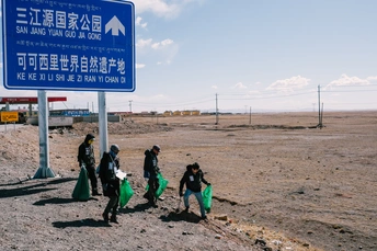 人们沿着一条路走 手里拿着垃圾袋。
