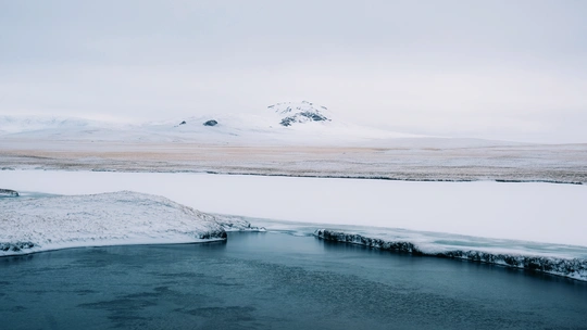 雪地上的河流或溪流 周围有山脉作为背景