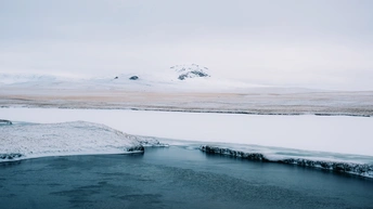 雪地上的河流或溪流 周围有山脉作为背景