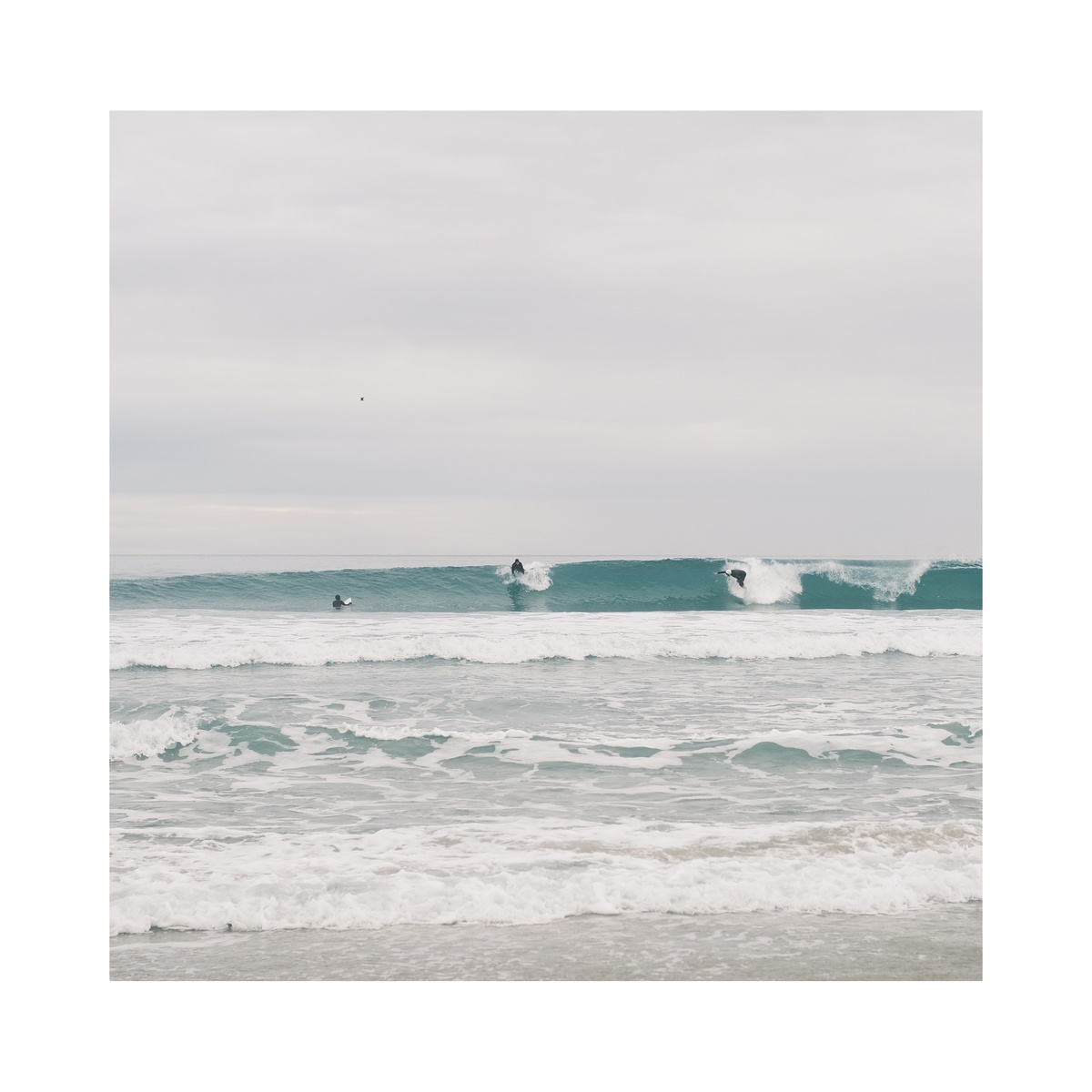 一张来自海滩的冲浪者骑着海浪的照片