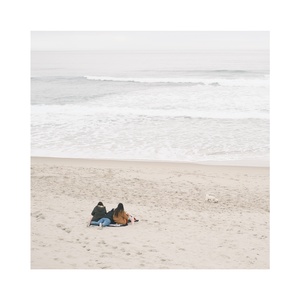 一个人和一只狗躺在沙滩上 背景是海洋。