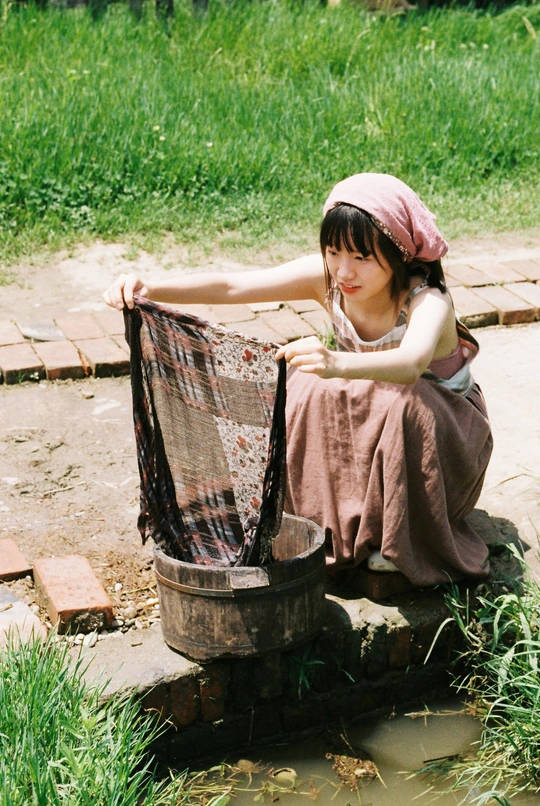 一个年轻的女人坐在小溪边的水桶里