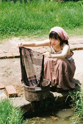 一个年轻的女人坐在小溪边的水桶里