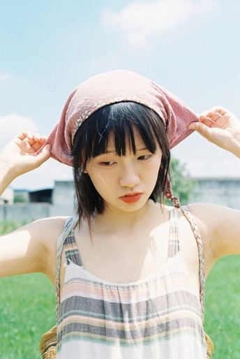 一个戴着粉色帽子的年轻女子站在草地上