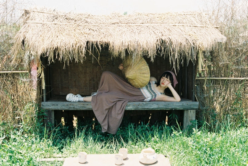一个女人躺在草地上一个避难所下面的长椅上