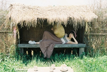 一个女人躺在草地上一个避难所下面的长椅上