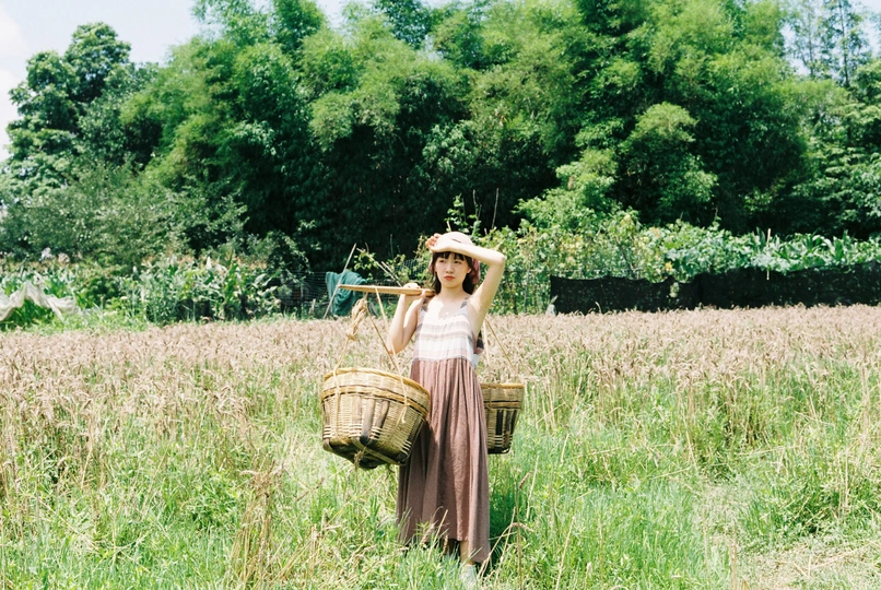 一位年轻的女士拿着篮子穿过一片高高的草地