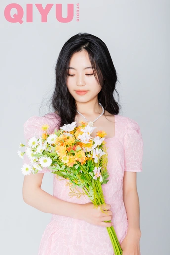 一位穿着粉红色连衣裙的年轻女子抱着一束花