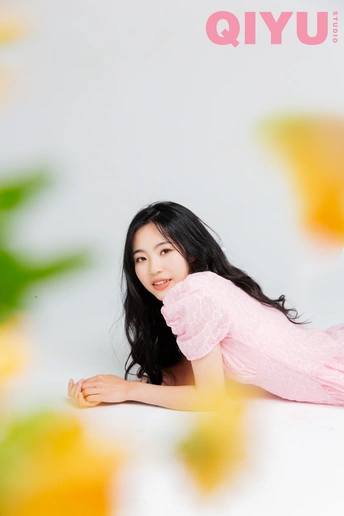 一位穿着粉红色裙子的女孩躺在有花做背景的人的封面