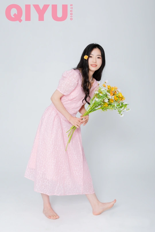 一位穿着粉红色连衣裙的年轻女子抱着一束花