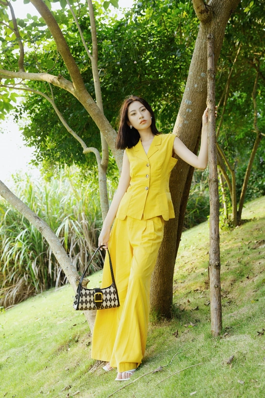 一位穿着黄色连衣裙站在一棵树旁的女士